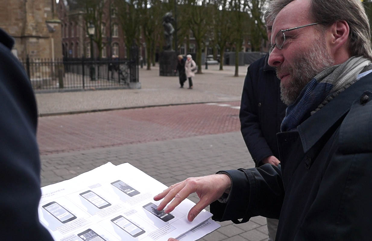 Gebruikersonderzoek op straat: een geprinte flow van mockups wordt besproken met een bezoeker in Den Bosch
